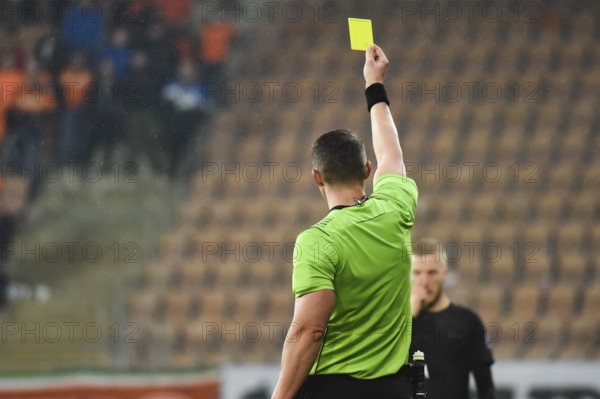 Referee shows footballer yellow card during soccer match at the stadium