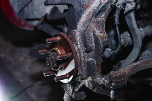 Rusty vehicle brake disc mount without the disc attached in a dim workshop setting