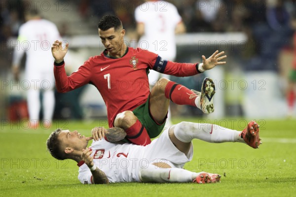 Football match, captain Cristiano RONALDO CR7 Portugal on the stomach of Kamil PIATKOWSKI Poland kneeling with his left leg and falling backwards with his right leg raised, hands outstretched upwards, looking at his opponent, Kamil PIATKOWSKI Poland lying on the ground on the grass screaming with his left leg up and direct eye contact with Cristiano RONALDO Portugal, Estadio do Dragao, Porto, Portugal, Europe