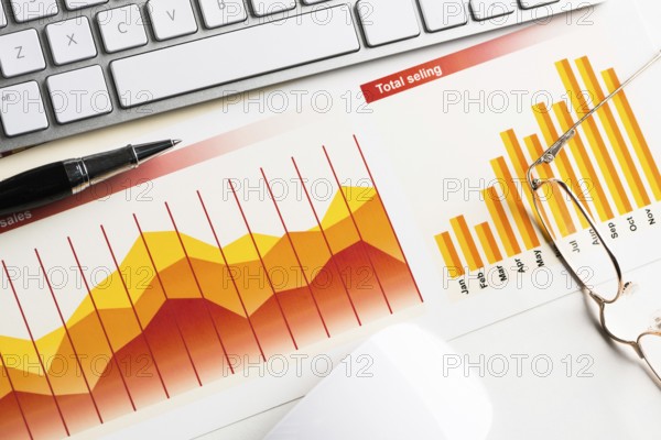 Business workplace with keyboard mouse and papers with graphs and diagrams