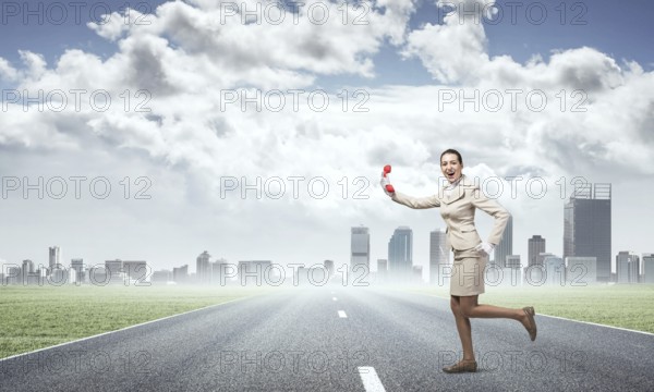 Woman running outdoor with vintage red phone. Expressive secretary with telephone on background downtown. Hotline telemarketing and communication. Professional business assistance and support