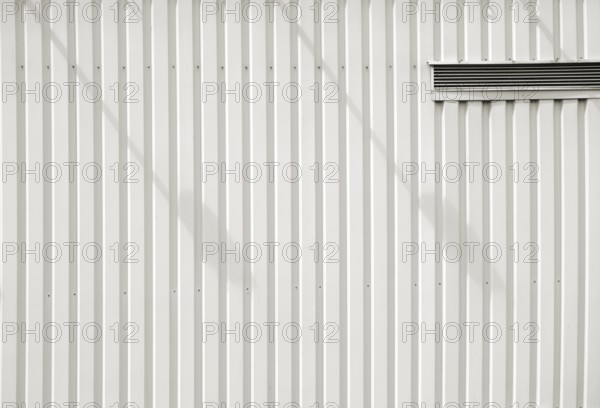 A modern façade of a shopping centre and DIY store made of checker plate with a ventilation slot and shade