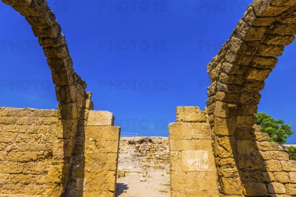Ruins of ancient Caesarea against the background of the blue southern sky. Excursion to the Archaeological Park of the Roman Empire. The concept of phototourism