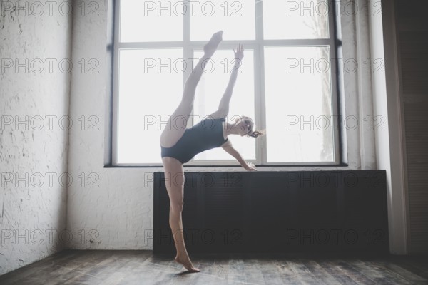 Plasticity slim woman dancing near window. Professional dancer enjoy dance. Lady Dancer Training Modern Ballet In Class. Contemporary dance performer. Daylight, silhouette beautiful body. Dance theme