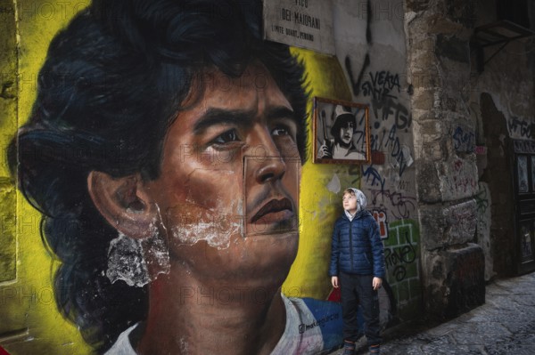 NAPLES, ITALY - JANUARY 14, 2024: Graffiti image of legendary FC Neapoli and Argentine national football player Diego Maradona and young boy