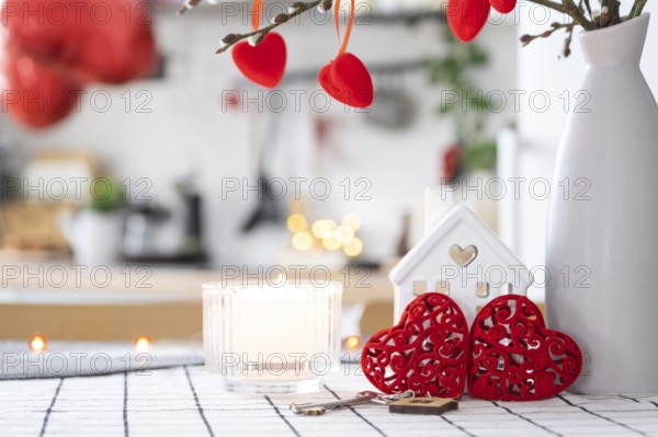 Key to house of cozy home with Valentine decor on table of kitchen. Gift for valentines day, family love nest. Building, design, project, moving to new house, mortgage, rent and purchase real estate