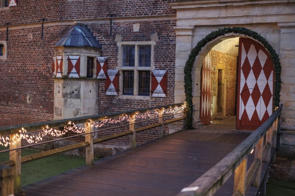 Castle bridge with lights leads to a large entrance gate, Rasfeld, Münsterland, North Rhine-Westphalia, Germany, Europe