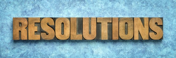Resolutions word abstract in vintage letterpress wood type blocks against blue textured bark paper, goal setting concept