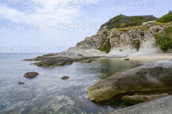Calm turquoise waters gently lapping against a rocky coastline under a serene sky on elba island, italy