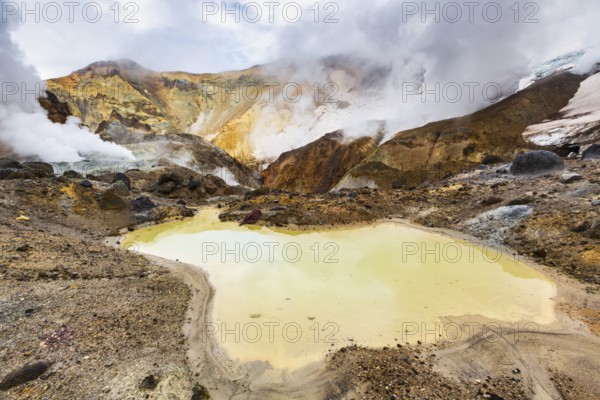 Lake in crater of active volcano. Beautiful dramatic volcanic landscape: hot spring, fumarole, geothermal gas-steam activity. Popular travel destinations for hike, active vacation, mountain climbing
