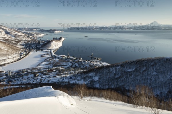 Beautiful winter Kamchatka landscape: top panoramic view of the Petropavlovsk-Kamchatsky City, Avachinskaya Bay and Pacific Ocean at sunset. Russia, Far East, Kamchatka Peninsula. (Evening lighting.)