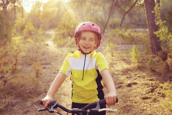 Kid girl biker in mountain bike MTB at mediterranean forest