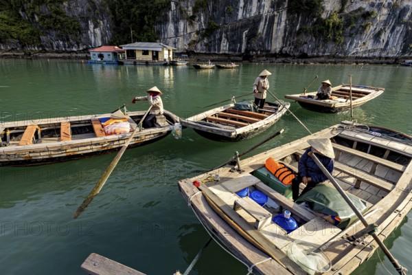 Boats with people in front of a rock, during a calm river trip, rowing boats for tourists in Halong Bay in Vietnam