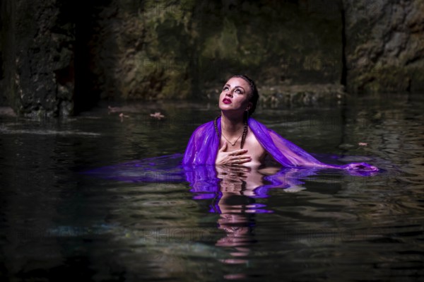 A beautiful nude latin model enjoys the gorgeous water in a colorful cenotes in Yucatan Merida, Cuzama, Mexico, Central America
