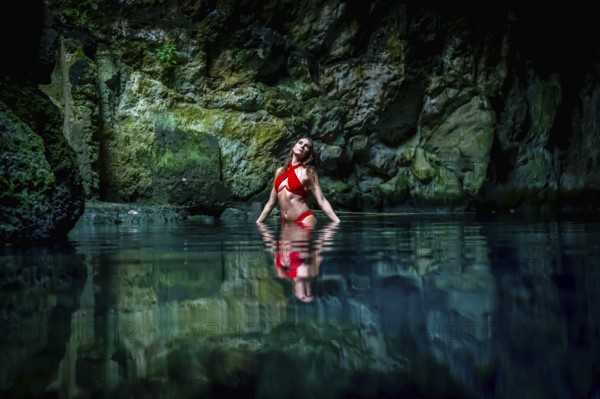 In Cuzama, Yucatan, Mexico, a stunning model revels in the vibrant hues of a cenote's blue and green waters, creating a picturesque scene of natural beauty, Cuzama, Mexico, Central America