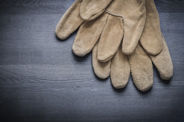 Two safety gloves on dark wooden board