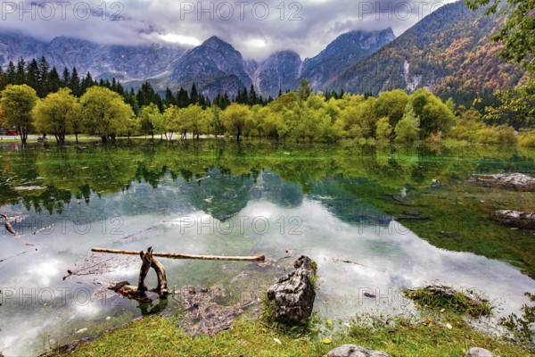 The lake shores are flooded. Picturesque shallow lake Fuzine of glacial origin. The mountains are covered with low clouds. Midday on an autumn day