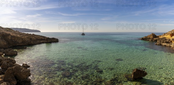 Panorama landscape view of an idyllic cove at Es Cap Enderrocat in southern Mallorca with a sailboat at anchor