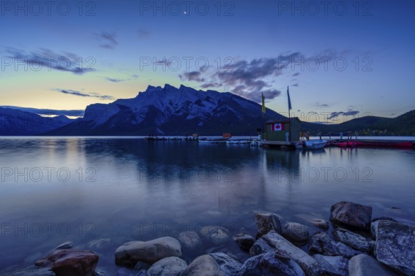 Beautiful autumn landscape scene in lake and mountain in background in west Canada, colour kayaks and canoes and small boats