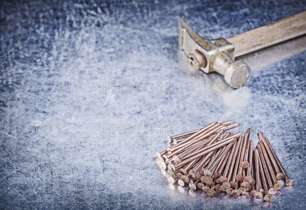 Vintage claw hammer stack of copper construction nails on metallic background