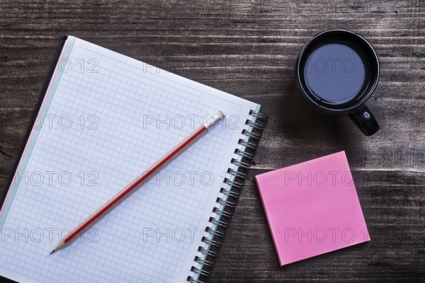 Open notepad pencil reminder note and cup of coffee on wooden board office concept
