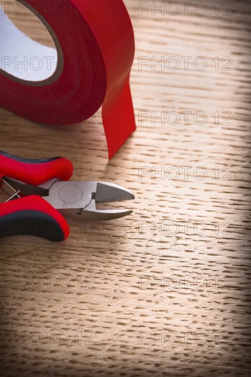 Vertical view nippers with insulating tape on wooden board