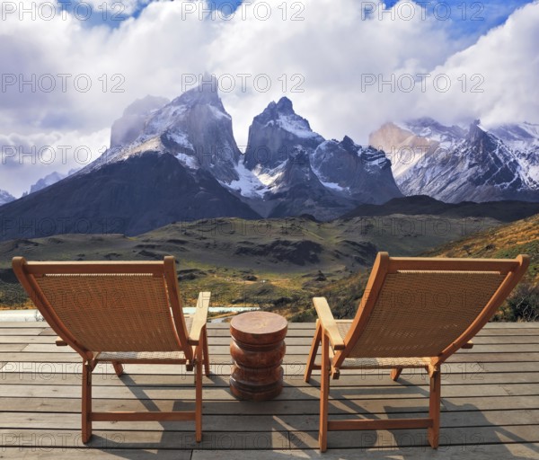 Comfortable lounge chairs on wooden platform for rest and observation. Gorgeous snow-covered rocks in the national park Torres del Paine