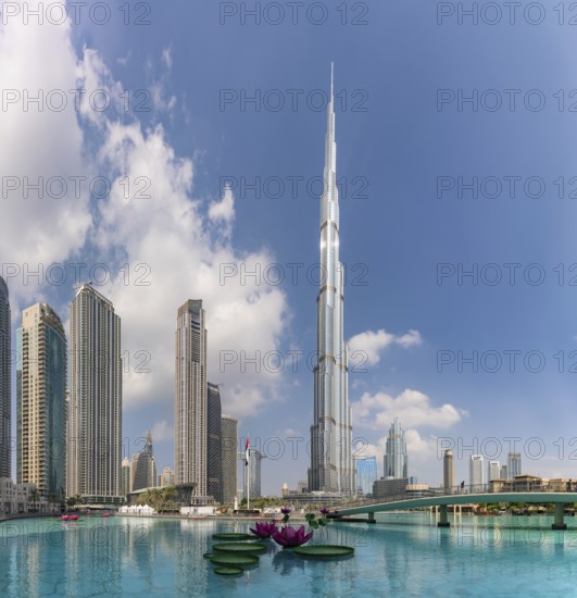 A picture of the Burj Khalifa towering the nearby Downtown Dubai buildings and the blue waters of the Burj Khalifa Lake