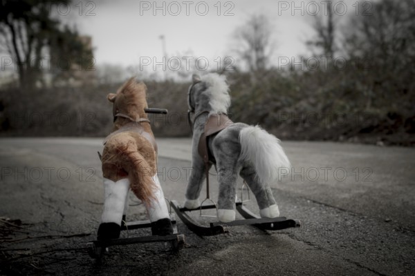 Two toy horses lie abandoned on the roadside