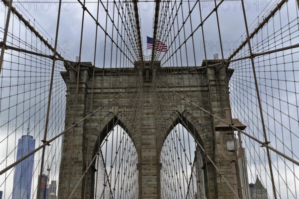 Brooklyn Bridge in Brooklyn, Manhattan, New York, USA United States of America, Symmetrical view of the Brooklyn Bridge with skyscrapers and flag in the background, New York City, USA, North America