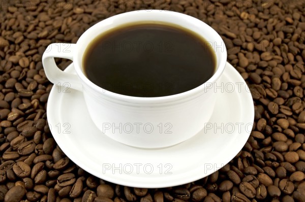 Coffee in a white porcelain cup on the background of the coffee beans
