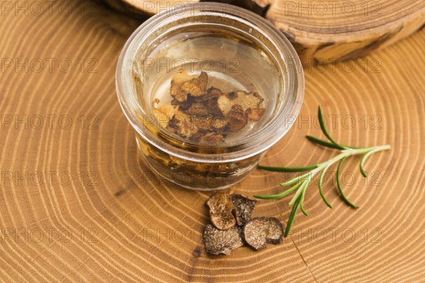 Sliced black truffle in olive oil in small jar and fresh rosemary