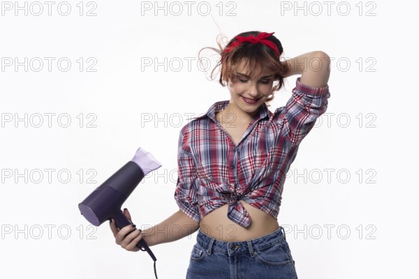 A stylish and fashionable young woman is playfully and joyfully using a hair dryer, showcasing her trendy style