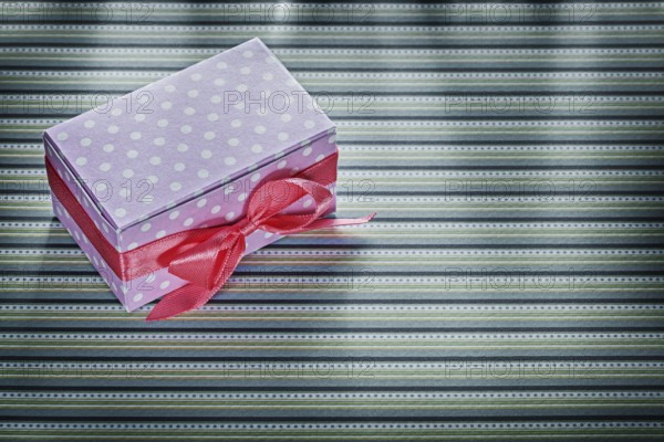 Pink gift box on stripy fabric celebrations concept