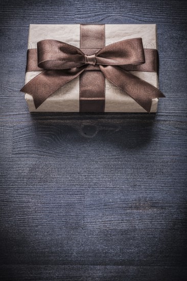 Gift box-container in wrapping paper on vintage wooden board