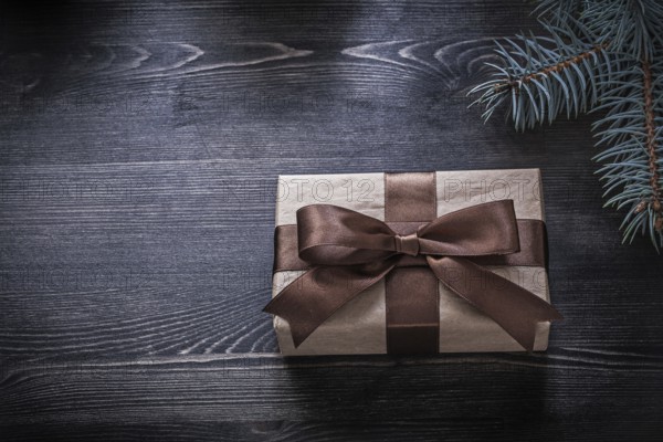 Pine branch wrapped gift box on wooden board holiday concept
