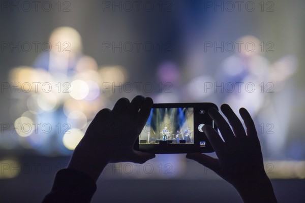 Fan holding smartphone and recording or taking picture during a concert