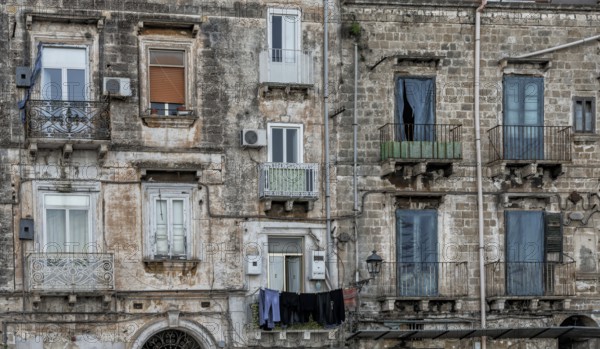 Taranto, Italy, 30 November, 2023: shabby chic derelict buildings with laundry hanging from the balconies in the Old Town of Taranto, Europe