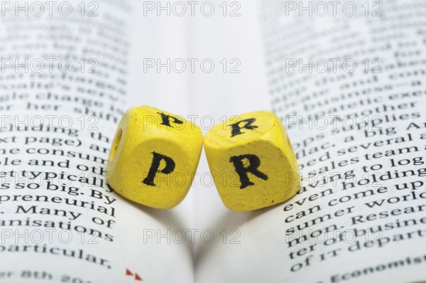 Word PR.Wooden cubes on newspaper. Close up studio shot