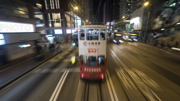 Traffic of public transport in night Hong Kong. Double-decker tram and buses driving in the city. Shot in motion