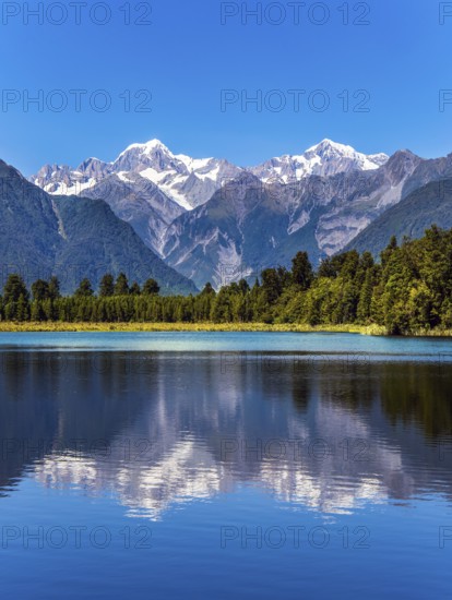The forests and Mount Cook and Mount Tasman. Magnificent snow-capped mountains surround the smooth, cold waters of Lake Matheson.The concept of ecological, active and photo tourism