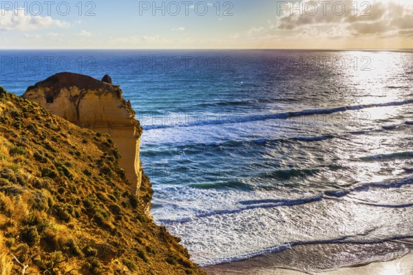 Powerful ocean surf at sunset. The Great Ocean Road. Steep and rocky ocean shore of Australia. The concept of exotic, active and photo-tourism