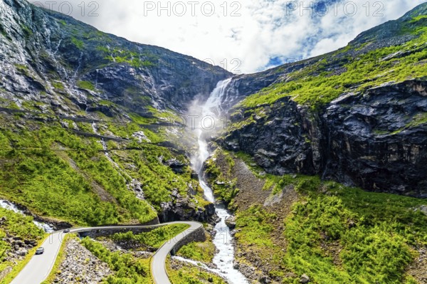 Trollstigen /Troll Staircase/ - the most popular tourist spot in Norway. The huge Stigfossen waterfall. The road serpentine meanders picturesquely on the green slopes of the canyon