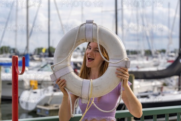 A gorgeous redhead model enjoys the perfect summer weather at a local marina, surrounded by boats of all kinds in the background, their reflections dancing on the water under the bright, sunny sky, Milwaukee, United States of America
