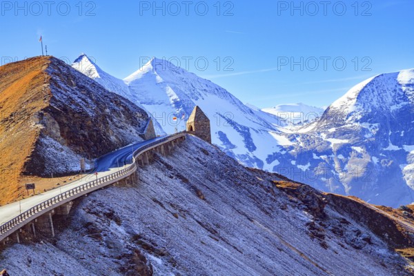 The famous panoramic mountain road Grossglocknerstrasse. Snow-capped mountain peaks are covered with clouds. Stone lookout tower at a sharp turn