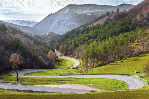 Winding mountain road serpentine after the rain. Wet asphalt. Cloudy winter day. Italy. Magnificent Umbria in December
