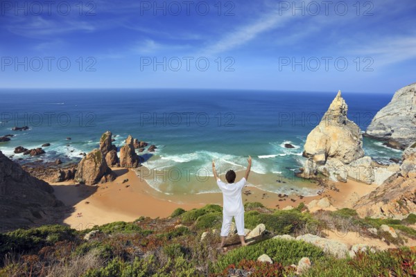 Small beautiful beach on the Atlantic coast. Middle-aged woman dressed in white doing yoga. The seaside resort of Sintra