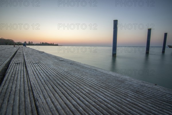 Sunrise on the shore and harbour of a lake in summer. Colourful sky with a wide view of the horiont. Natural landscape at Tihany marina, Lake Balaton, Lake Balaton, Siófok, Hungary, Europe