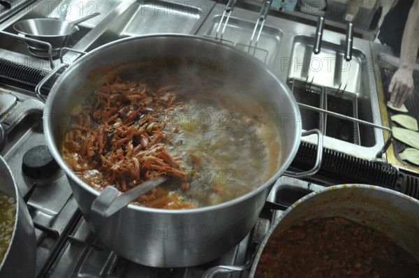 Shrimp boiling in a large pot on a stove in a busy kitchen setting, Cooks and chefs prepare dinner with the typical Mediterranean Diet at a luxury resort in Sciacca, Sicily