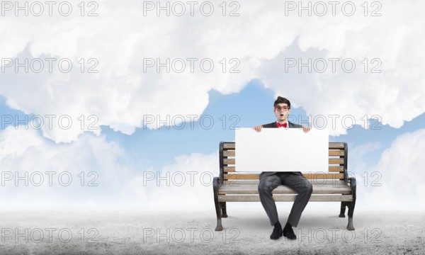 Young businessman holds a large white banner. sits on the bench